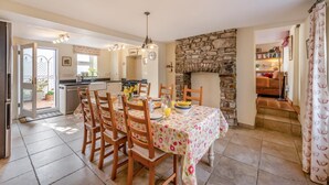 A dining area with a stone fireplace, wooden chairs, and a table set for a meal.