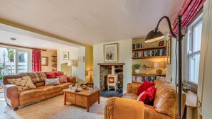 A cozy living room with a fireplace, leather sofas, a coffee table, and a bookshelf filled with books.