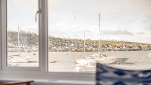 A view from a window overlooking a harbor with boats and a coastal town.