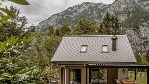 Ein modernes Haus mit einer überdachten Terrasse, einem Essbereich und Bergblick.