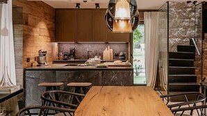 Eine moderne Küche mit einem Holzespeisetisch und -stühlen, einer Pendelleuchte und Blick ins Freie.