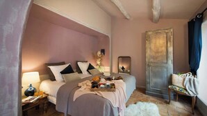 A bedroom with a bed, bedside table, lamp, and a mirror. - Luxury Suite, terrace, private pool and jacuzzi (Noves)