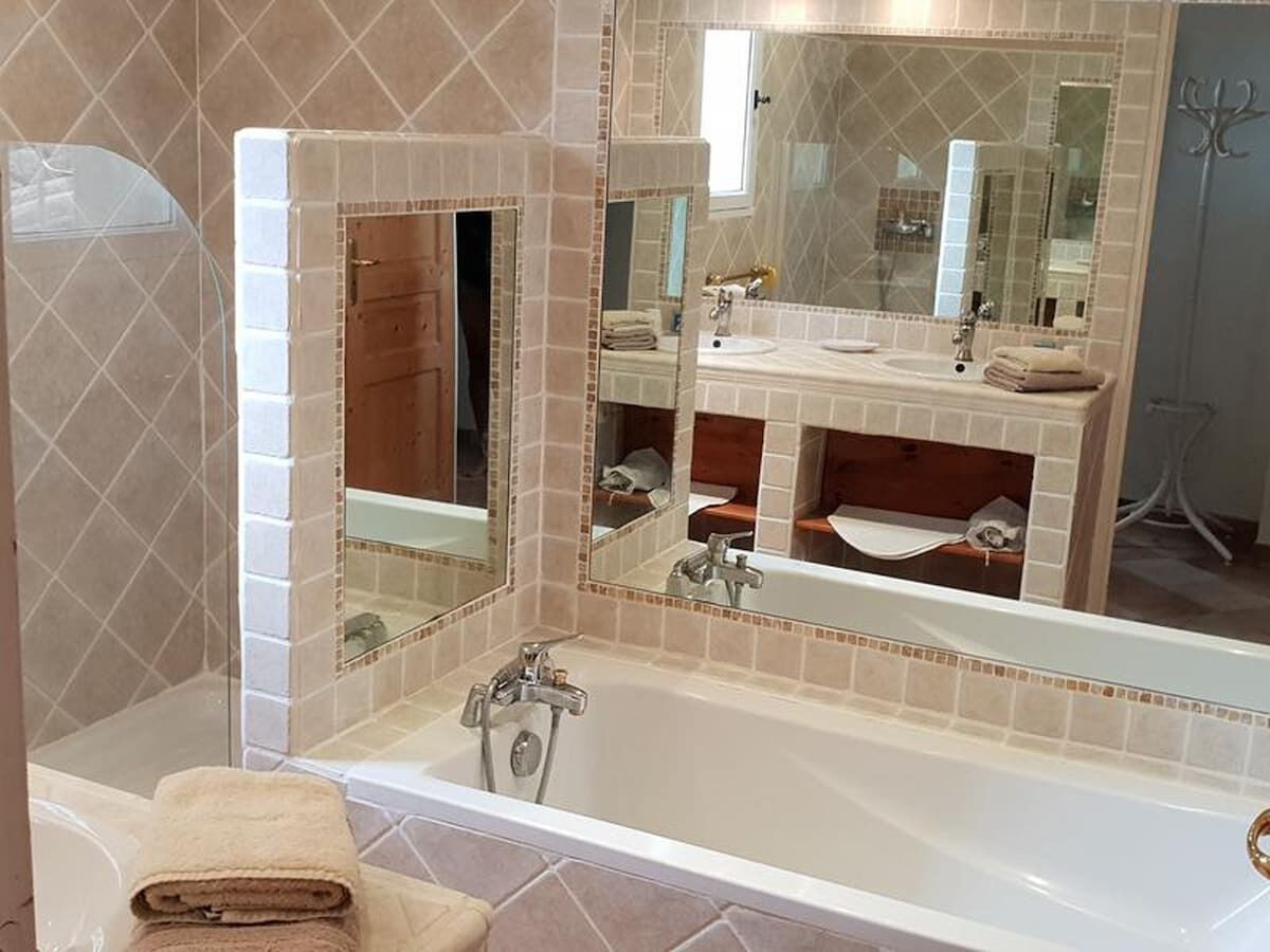 A bathroom with a bathtub, a sink, and a large mirror.
