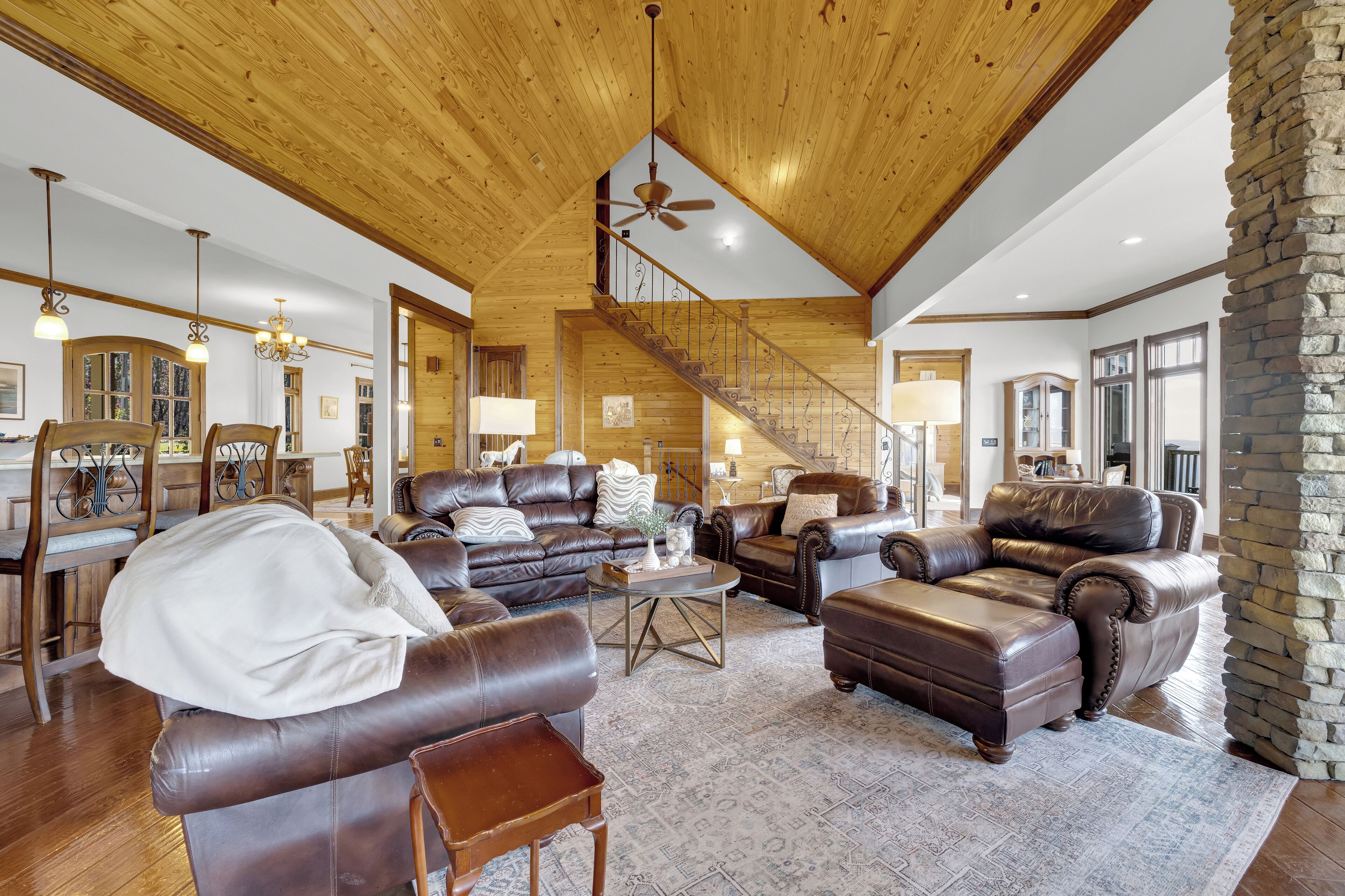 A spacious living room with leather sofas, a coffee table, and a staircase leading to another level.