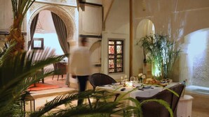 A dining area with a table set for two, a large potted plant, and a doorway leading to another room. - Sublime suite in a magnificent Riad with Pool (Marrakesh)