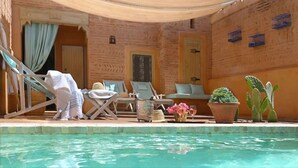 A poolside area with lounge chairs, a small table with drinks, and potted plants. - Sublime suite at Riad Douceur with oriental decor (Marrakesh)