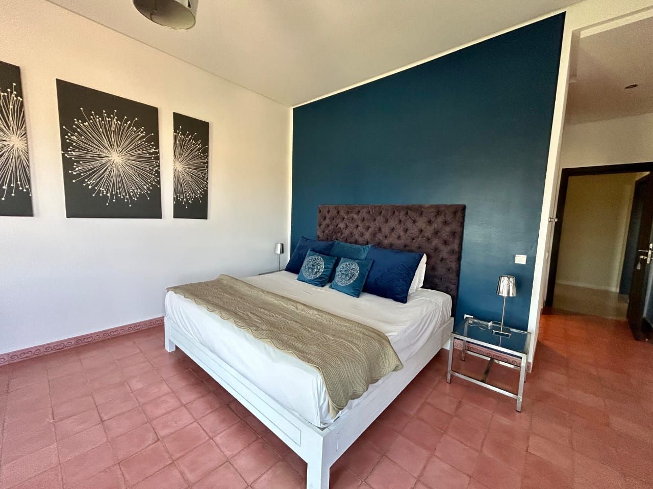 A bedroom with a bed, a headboard, a nightstand, and three wall art pieces.
