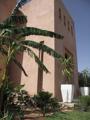 A building with a curved facade, a palm tree, and a rock garden. - Villa Sylana 2 Pools Tennis Court Hammam (Marrakesh)