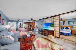A living room with a sofa, TV, and a dining area with chairs and a table.