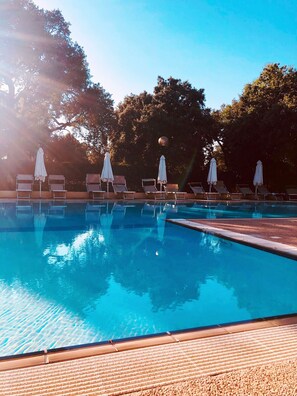 A swimming pool with lounge chairs and umbrellas, surrounded by trees. - Nuraghe Ruiu Campeggio Villaggio (Norbello)
