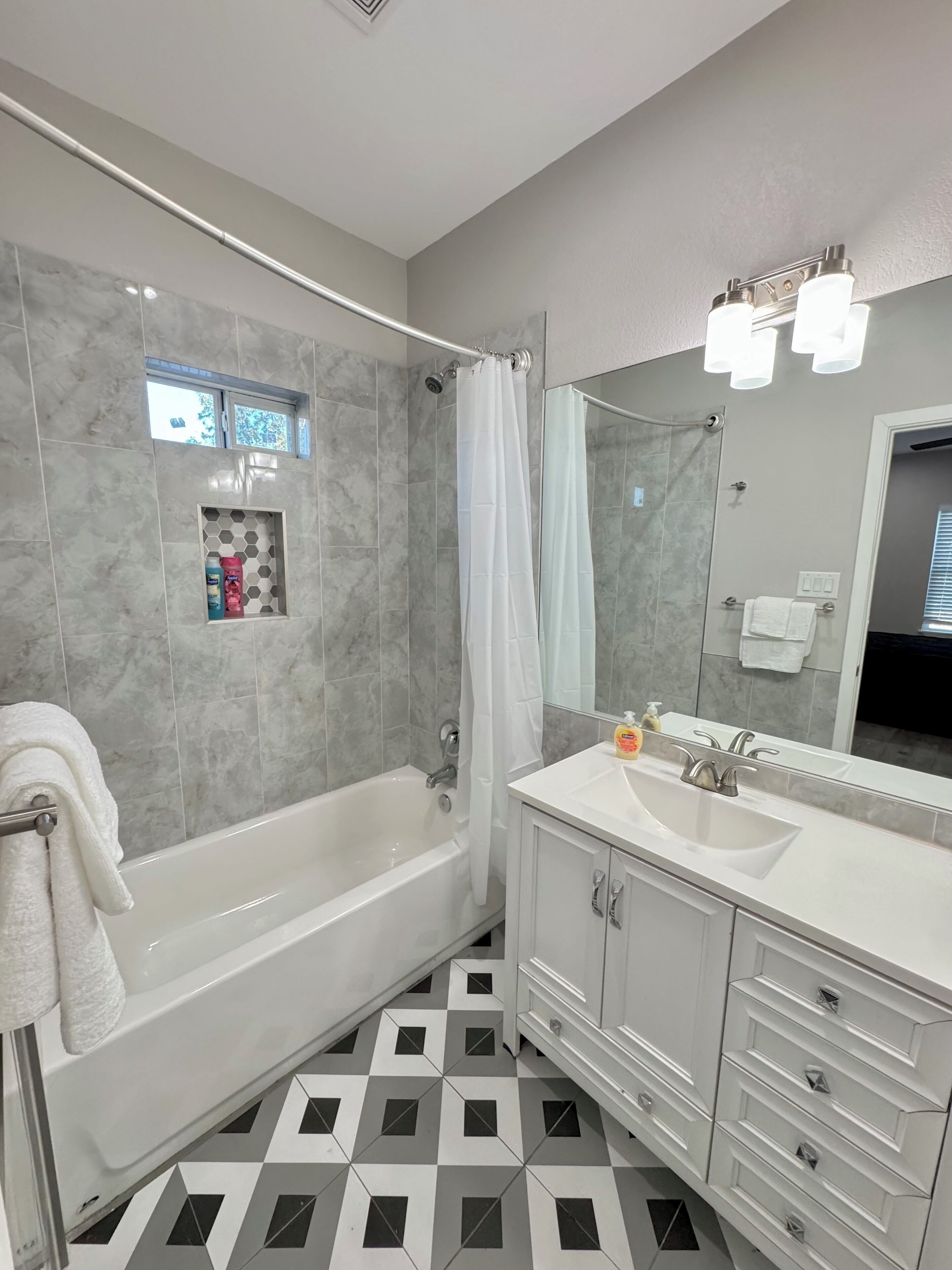 Une salle de bain moderne équipée d’une baignoire, d’une douche et d’un meuble-lavabo avec un miroir.