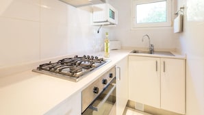A modern kitchen with a gas stove, oven, microwave, and a window above the sink. - Apartment Near Romerbad Thermal Spa (Bad Kleinkirchheim)