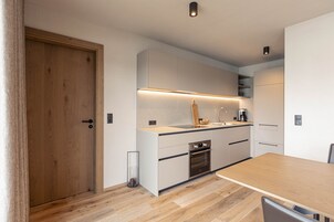 Una cocina moderna con puerta de madera, armarios empotrados, encimera y horno integrado.