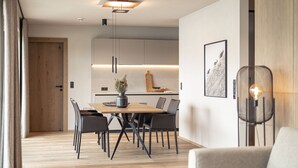 A modern dining area with a wooden table and chairs, a pendant light, and a framed picture on the wall. - Beautiful Apartment in Tyrol With Terrace (Westendorf)
