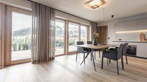 A modern kitchen with a dining area, large windows, and a view of the outdoors. - Beautiful Apartment in Tyrol With Terrace (Westendorf)