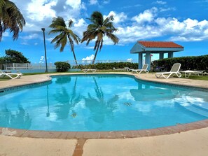 A swimming pool with lounge chairs, palm trees, and a gazebo. - 2 BR Beach Resort Apt with WiFi and access to the beach (Medianía Alta)