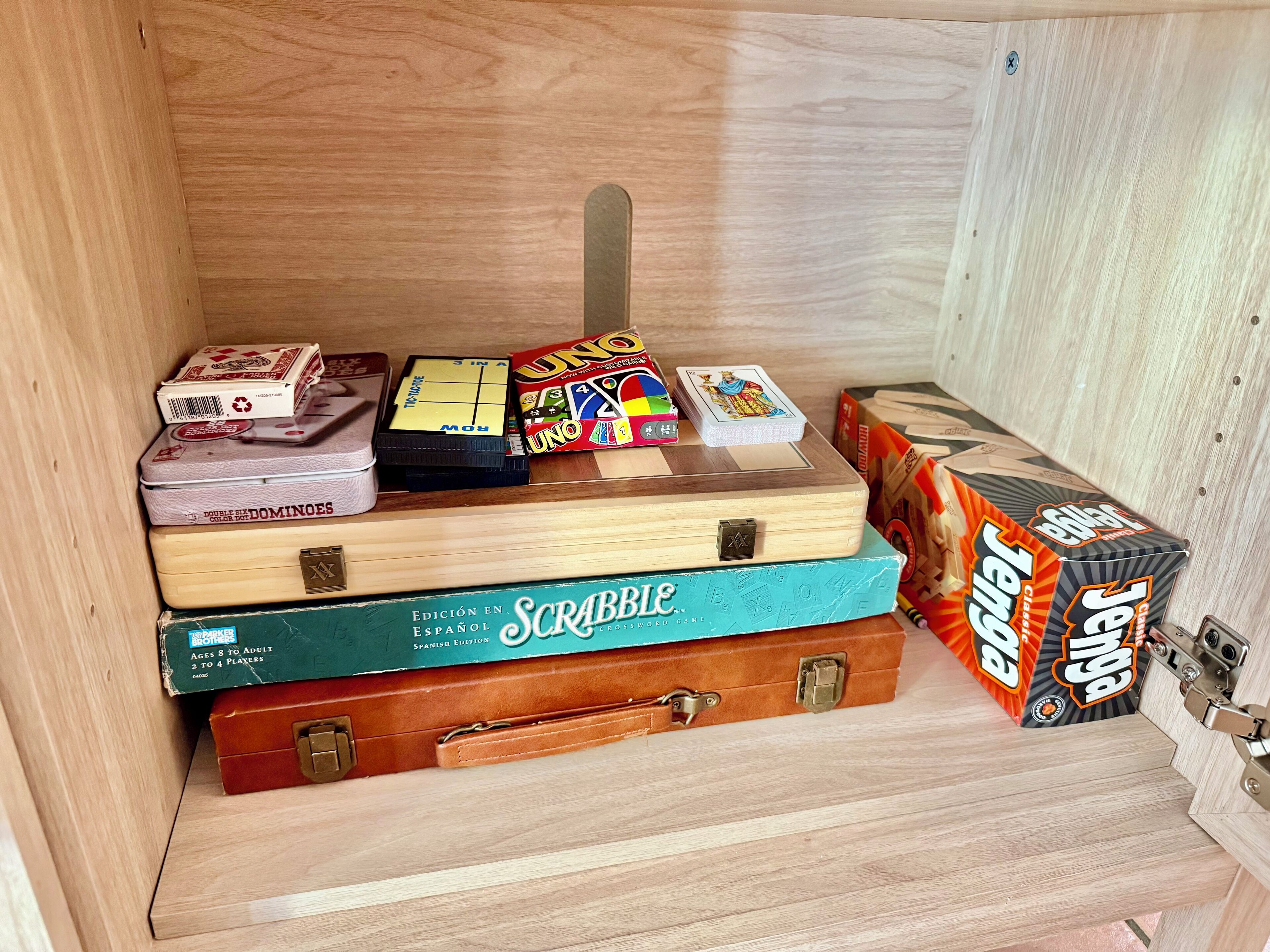 Ein Holzkabinent mit verschiedenen Gesellschaftsspielen und einer Scrabble-Box.
