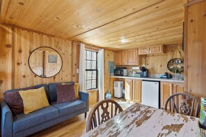 Cozy cabin-style room with a comfortable sofa, dining table, and kitchen area.