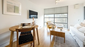 A modern living room with a dining area, a sofa, a TV, and a large window. - Modern Flat, Oxford city centre (Oxford)