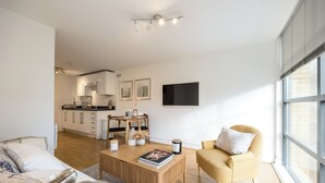 A modern living room with a sofa, a yellow armchair, a coffee table, and a dining area with a wooden table and chairs. - Modern Flat, Oxford city centre (Oxford)