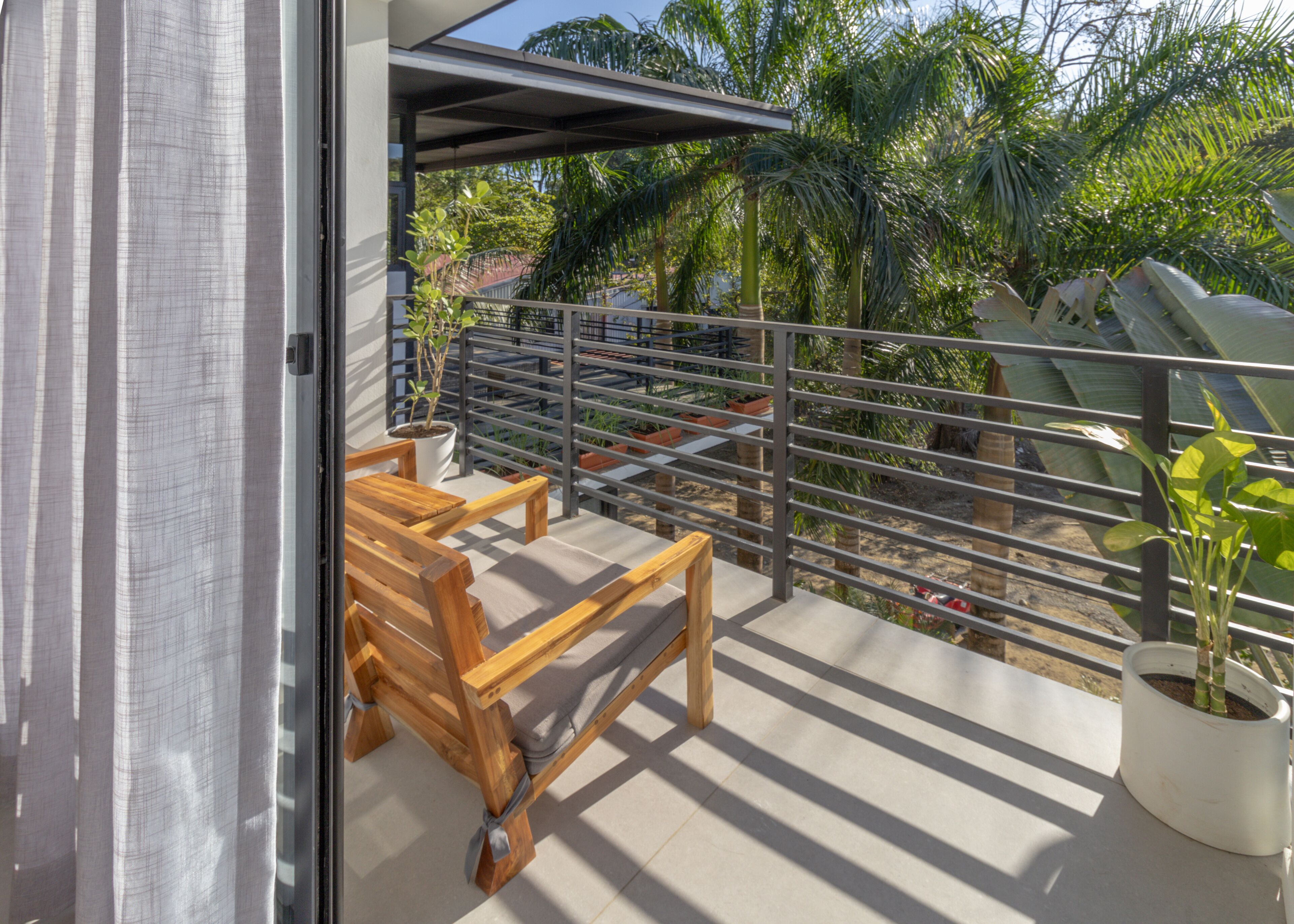 Ein Balkon mit einer hölzernen Bank, Kübelpflanzen und einem Metallgeländer.