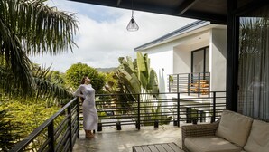 A balcony with a wicker sofa, a railing, and a large plant. - Casa Swell Boutique Hotel  (Cóbano)