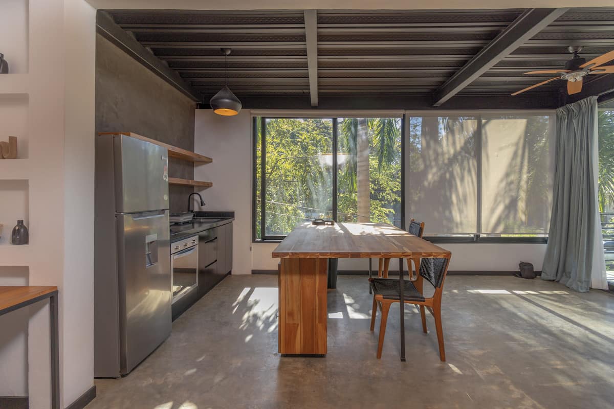 Una cocina moderna con una isla grande, electrodomésticos de acero inoxidable y vistas al exterior a través de amplios ventanales.