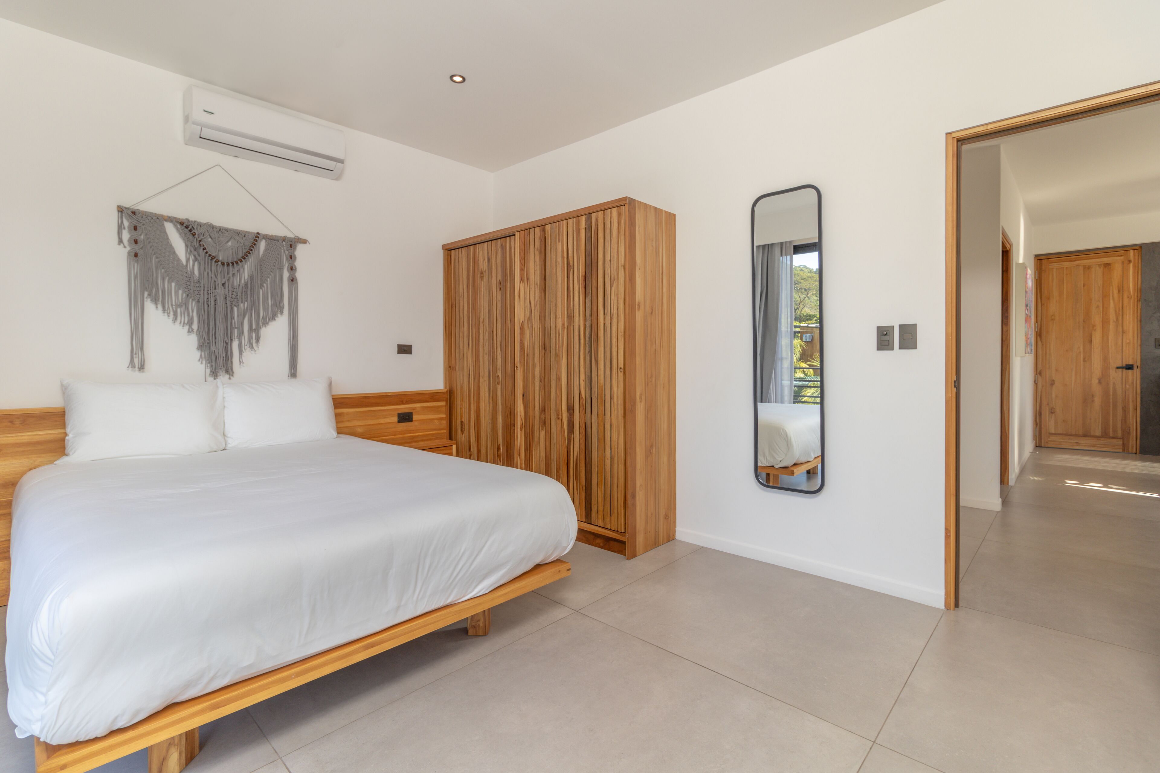 Een slaapkamer met een houten bed, een kledingkast en een spiegel aan de muur.