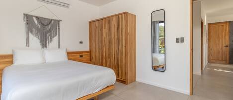 Een slaapkamer met een houten bed, een kledingkast en een spiegel aan de muur.