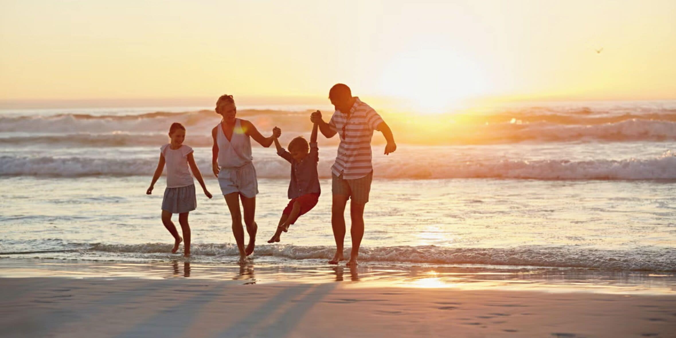 A family walking along a beach at sunset.
