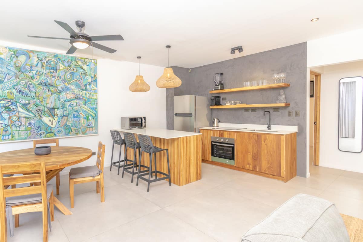 Una cocina moderna con una isla central, armarios de madera y un comedor con mesa y sillas.