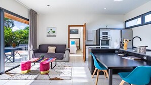 Un espacio de estar moderno con sofá, mesa de centro y área de cocina con mesa y sillas para comer.