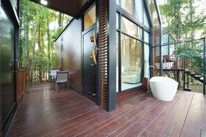 A modern house with a wooden deck, a large glass window, and a white bathtub. - High Tree Resort Co.,Ltd. (Krabi)