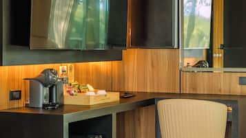 A modern kitchen with wooden cabinetry, a built-in refrigerator, a coffee machine, and a seating area with a chair.