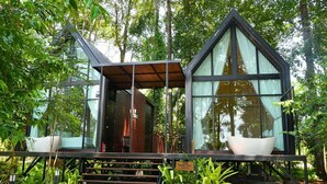 A modern cabin with a wooden deck, large windows, and a white bathtub.