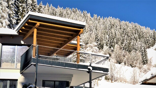Un bâtiment moderne doté d’un balcon et offrant une vue sur des arbres couverts de neige.