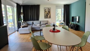 Un salon moderne comprenant un canapé, une table à manger, des chaises et un téléviseur.