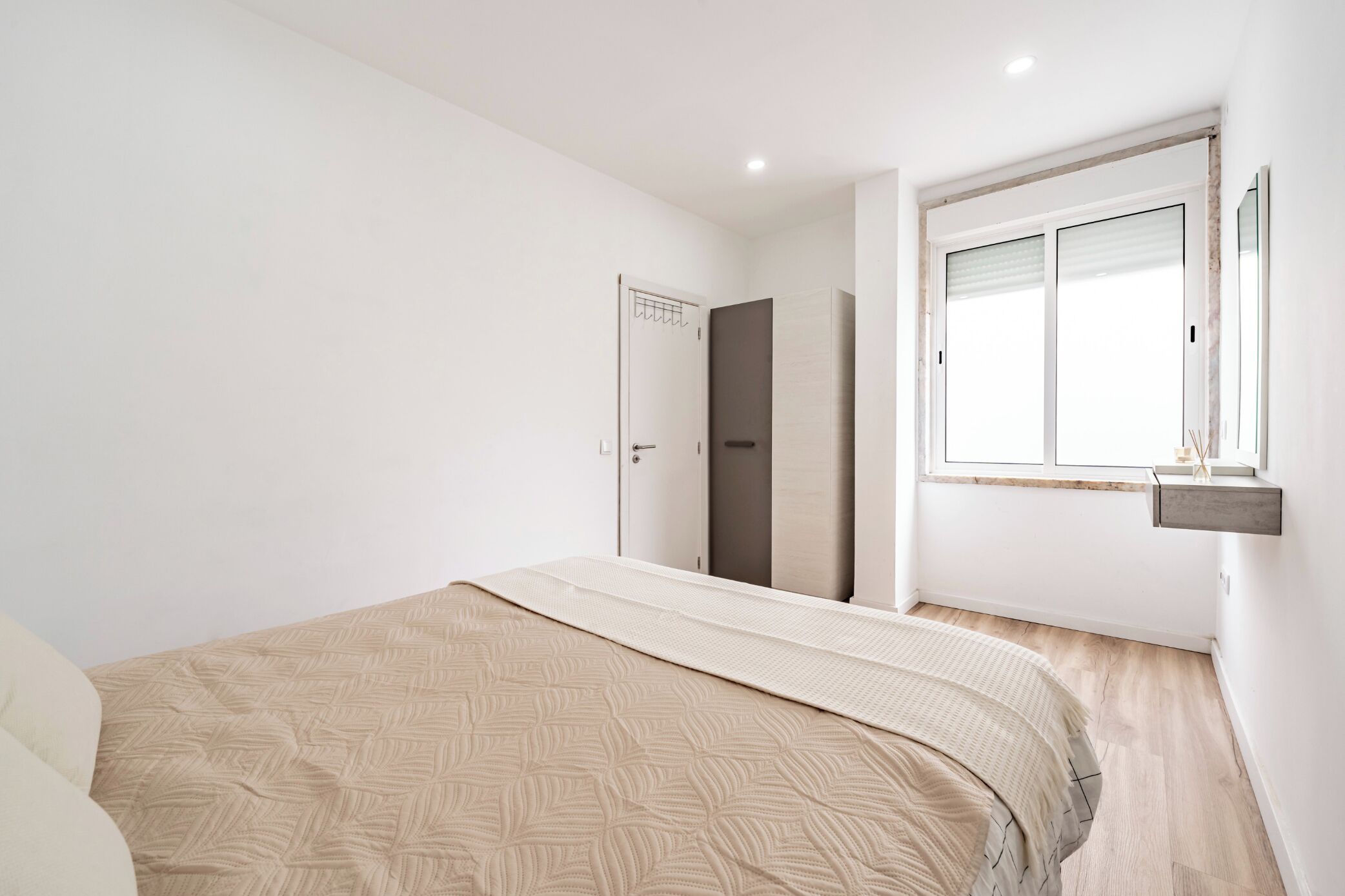 Een slaapkamer met een bed, een kledingkast, een raam en een spiegel.