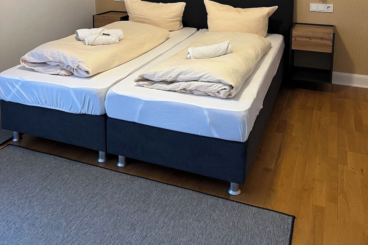 A double bed with two pillows, a bedside table, and a nightstand.