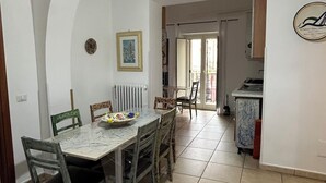 A dining area with a marble table and wooden chairs, a radiator, and a framed picture on the wall. - Apartment sea view GAETA (Gaeta)