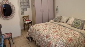 A bedroom with a floral bedspread, a chair, a wardrobe, and a mirror. - Apartment sea view GAETA (Gaeta)