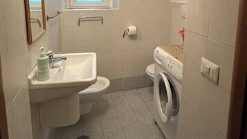 Un baño pequeño con lavamanos, inodoro y lavadora.