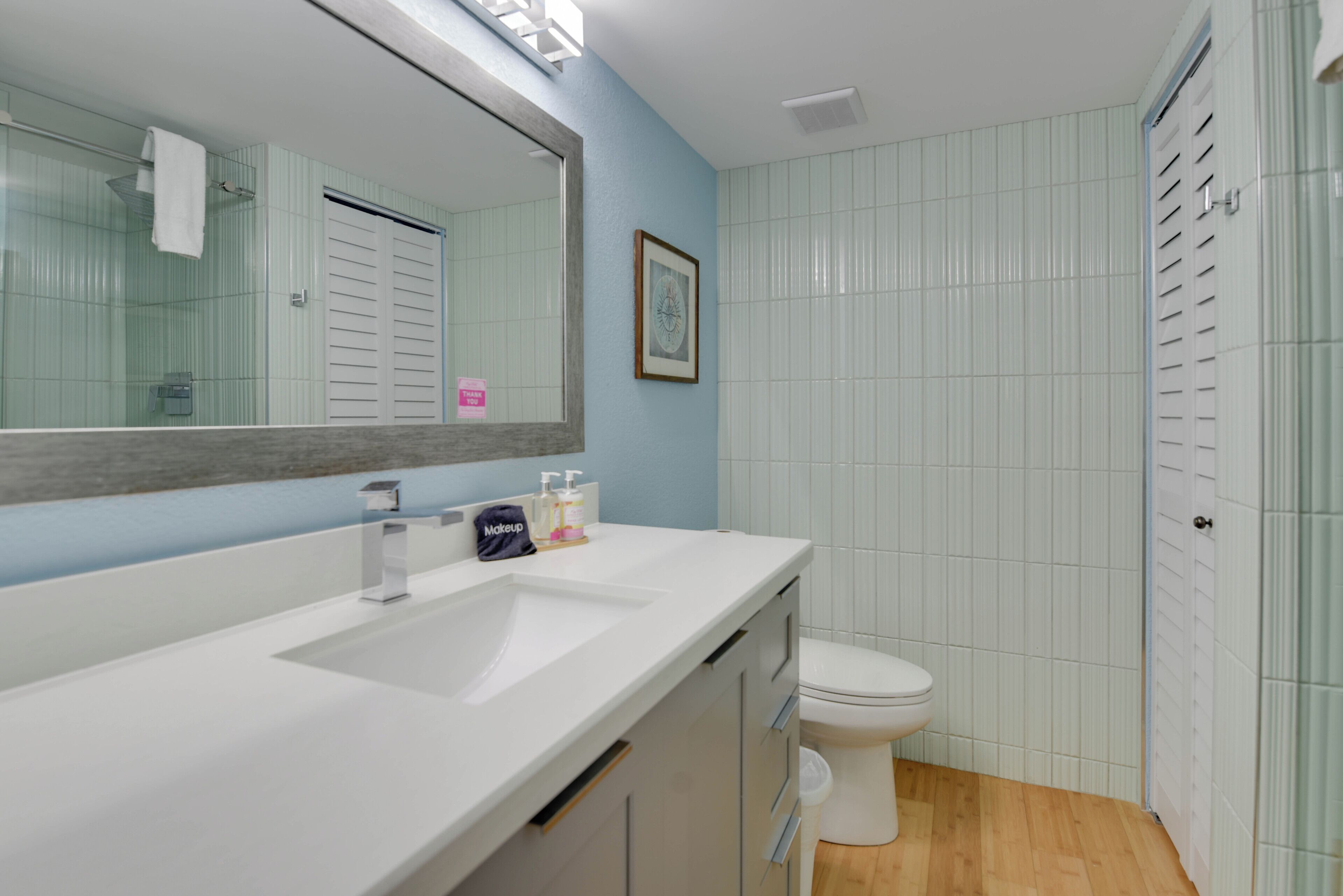 A bathroom with a white sink, a mirror, a toilet, and a shower area.