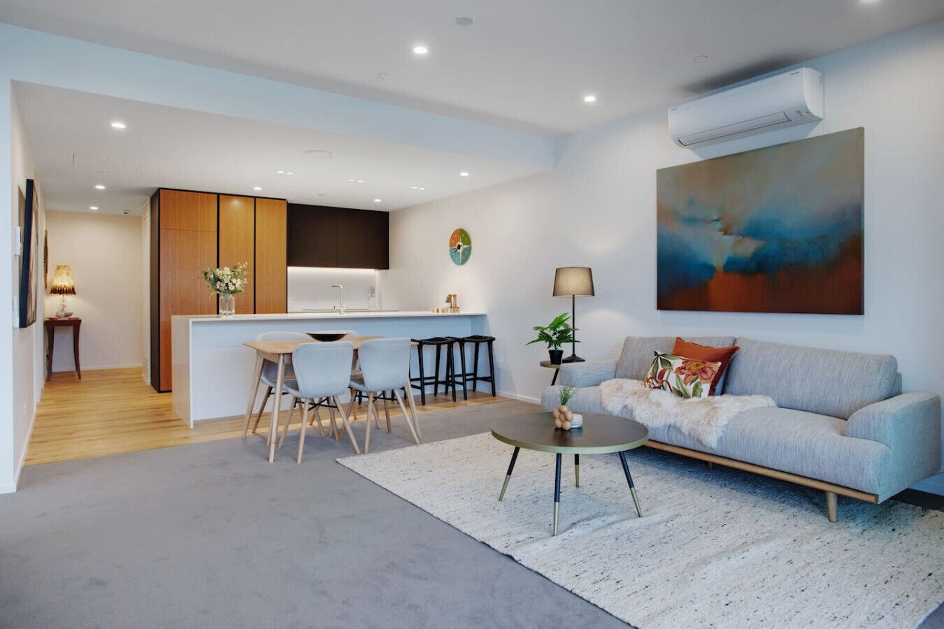 A modern living room with a sofa, coffee table, and dining area.