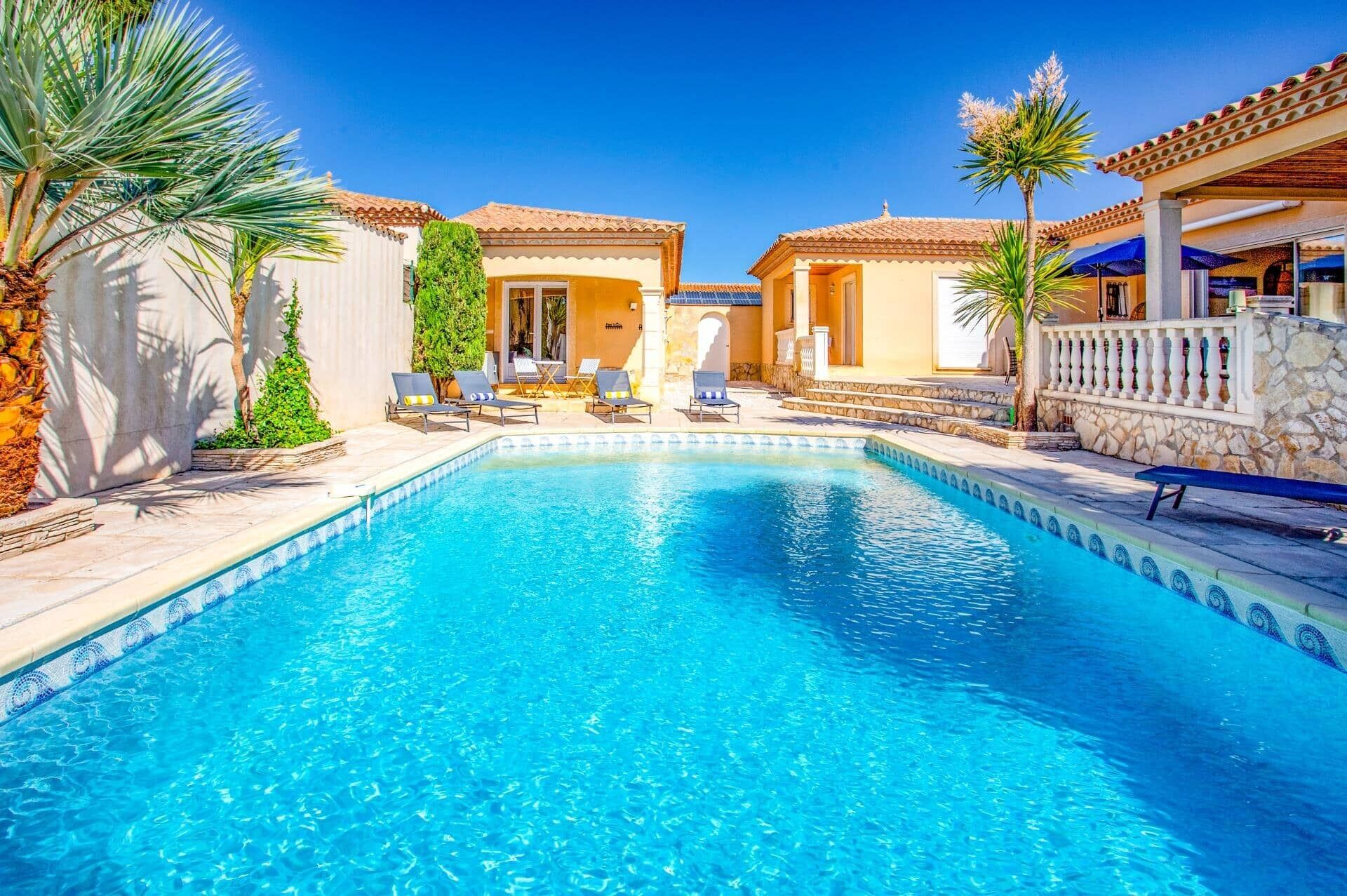 A swimming pool with lounge chairs and a stone wall.