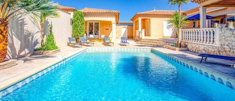 A swimming pool with lounge chairs and a stone wall.