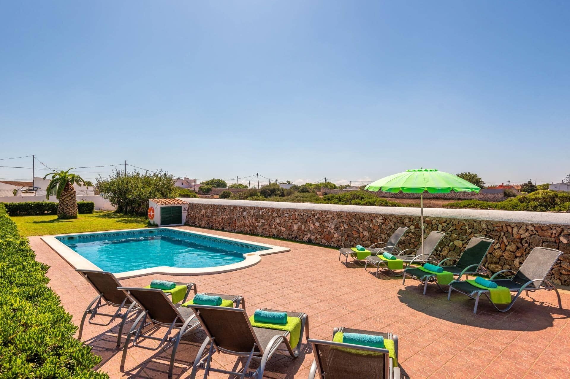 Ein Swimmingpool mit Liegestühlen und einem grünen Sonnenschirm.