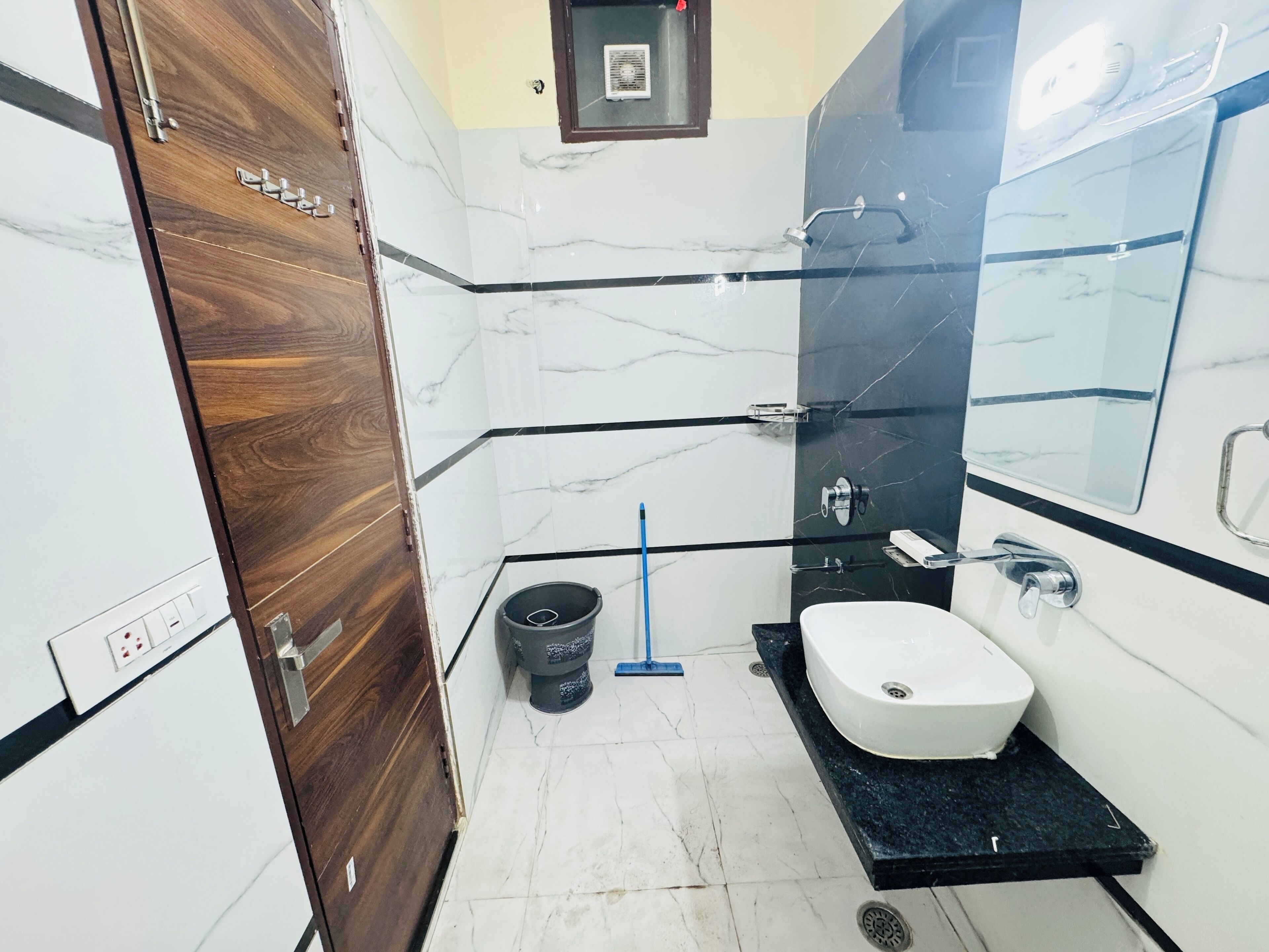 A bathroom with a white sink, black countertop, and marble walls.