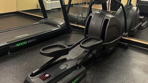 A gym with treadmills, elliptical machines, and a mirrored wall.