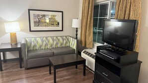 A living room with a sofa, a coffee table, a TV, and a lamp.